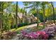 Elegant stone home with manicured landscaping, flowering bushes, and a charming gated entrance at 105 Kingston Mnr, Atlanta, GA 30342