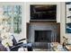 Close-up of the stone fireplace with mounted TV, stylish seating, and elegant flower arrangement next to a bright window at 105 Kingston Mnr, Atlanta, GA 30342