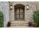Elegant double doors with arched brick surround, flanked by sconces and planters with vibrant flowers at 105 Kingston Mnr, Atlanta, GA 30342
