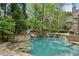 Stone pool features rock waterfall, hot tub and is surrounded by trees and lush landscaping at 105 Kingston Mnr, Atlanta, GA 30342