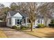 Charming cottage-style home featuring a covered porch, beautiful landscaping, and a driveway leading to the house at 27 Spence Ne Ave, Atlanta, GA 30317