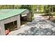 Large storage building with a green metal roof, partially open side and gravel drive at 175 Flat Creek Ct, Fayetteville, GA 30214