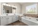 Bright bathroom featuring a double vanity with a soaking tub, and a window with natural light at 2238 Well Springs Dr, Buford, GA 30519