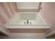 A large white bathtub with tiled trim and fixtures at 2261 Byron Sw Ct, Marietta, GA 30064