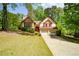 Two-story home with Tudor architecture, featuring a two-car garage, mature trees, and a lush green front lawn at 2261 Byron Sw Ct, Marietta, GA 30064