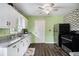 A well-lit kitchen showcases a modern ceiling fan and white cabinets with granite countertops and black appliances at 4061 Newman Ellis Rd, Douglasville, GA 30134