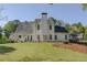 Beautiful backyard view featuring manicured lawn, patio seating, a well-maintained home exterior, and mature trees at 513 Huntgate Rd, Woodstock, GA 30189