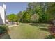 Expansive backyard with lush green grass, mature trees, and a serene patio seating area at 513 Huntgate Rd, Woodstock, GA 30189