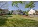 Lush backyard showcases mature trees, a well-kept lawn, patio furniture, and the home's elegant exterior at 513 Huntgate Rd, Woodstock, GA 30189