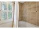 Well-lit bathroom with tiled walls, white shower curtain, and window with plantation shutters at 640 Sibley Se Frst, Marietta, GA 30067