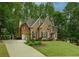 Charming brick home featuring a well-kept lawn, arched doorway, and convenient driveway access at 104 Fairway Overlook, Woodstock, GA 30188