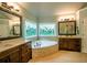 A luxurious bathroom boasts a large soaking tub, double sinks, and stunning stained glass windows at 104 Fairway Overlook, Woodstock, GA 30188
