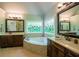 A luxurious bathroom boasts a large soaking tub, double sinks, and stunning stained glass windows at 104 Fairway Overlook, Woodstock, GA 30188