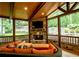 Enclosed sunroom with stone fireplace, wood ceilings, and scenic backyard views at 104 Fairway Overlook, Woodstock, GA 30188
