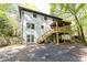 Backyard of white brick home featuring a covered deck, stairs, and wooded views at 4175 Valley Trail Se Dr, Atlanta, GA 30339