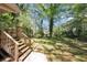 Large backyard with a wooden deck and stairs leading down to a lush green lawn surrounded by mature trees at 2650 Gwendon Ct, Decatur, GA 30034