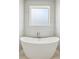 Elegant bathroom featuring a modern freestanding tub with a sleek faucet and a bright window for natural light at 1095 Lanier Pl, Cumming, GA 30041