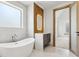 Bright bathroom showcasing a freestanding tub, sleek vanity with wood accents, and a glimpse into an adjacent room, creating an open feel at 1095 Lanier Pl, Cumming, GA 30041