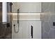 Modern tiled walk-in shower with black fixtures and a built-in shelf with lighting at 1095 Lanier Pl, Cumming, GA 30041