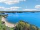 Breathtaking lake view with a sandy beach, lush greenery, and clear blue waters under a partly cloudy sky at 1095 Lanier Pl, Cumming, GA 30041