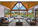 Staged covered patio with vaulted wood ceiling, black beams, comfortable furniture, and manicured backyard at 1095 Lanier Pl, Cumming, GA 30041