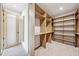 Large walk-in closet with custom wood shelving, carpet flooring, and light wood door at 1095 Lanier Pl, Cumming, GA 30041