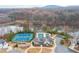 Aerial view showcasing a community clubhouse, pool, and tennis courts by a scenic lake with trees in the background at 3945 Starwood Dr, Cumming, GA 30028