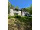 View of the back side of the home with porch, stairs, and surrounding trees at 1905 Rockmart Rd, Villa Rica, GA 30180