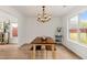 Bright dining room featuring an elegant chandelier, a wood table with bench seating, and large windows offering backyard views at 160 Fieldstone Dr, Powder Springs, GA 30127