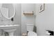 This powder room features a pedestal sink, oval mirror, floating shelf, and a neutral color palette at 248 Colony Center Dr, Woodstock, GA 30188