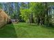 Spacious backyard with lush green grass and mature trees and partial view of house at 553 Candlewood Dr, Stone Mountain, GA 30088