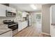 Modern kitchen with stainless appliances, white cabinets, and a view of the sunroom through a doorless entry at 553 Candlewood Dr, Stone Mountain, GA 30088