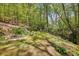Scenic backyard featuring a pathway, creek, storage shed, and lush landscaping at 3311 Stillhouse Se Rd, Atlanta, GA 30339