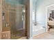 Bright bathroom featuring a tiled walk-in shower, separate tub, and access to the main bedroom at 5832 Sloane St, Douglasville, GA 30135