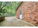 Brick house featuring a concrete patio and a white door facing a peaceful wooded area at 2520 Overlook Ne Way, Atlanta, GA 30345