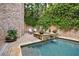 Backyard pool with spa, stone waterfall feature, beautiful greenery, and brick surround at 3250 Twisted Branches Ln, Marietta, GA 30068