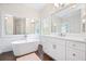 Bright bathroom with double vanities, freestanding tub, glass enclosed shower, and dark wood floor at 4201 Village Green Dr, Roswell, GA 30075