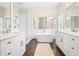 Bright bathroom with double vanities, freestanding tub, glass enclosed shower, and dark wood floor at 4201 Village Green Dr, Roswell, GA 30075