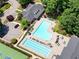 An aerial view showing a sparkling community pool with ample seating, next to a clubhouse and parking area at 4201 Village Green Dr, Roswell, GA 30075