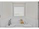 Modern bathroom with a soaking tub, white tile surround, and a window for natural light at 1325 Richland Creek Ct, Sugar Hill, GA 30518
