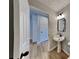 Elegant bathroom featuring a pedestal sink, modern lighting, and hardwood flooring at 132 Garden Manor Ct, Loganville, GA 30052