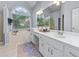 Bright bathroom with double sinks, white cabinets, and a large soaking tub by an arched window at 705 Branch Tree Way, Lawrenceville, GA 30043