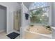 Bathroom featuring a soaking tub by a large window and a glass enclosed shower at 705 Branch Tree Way, Lawrenceville, GA 30043