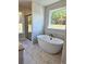 Luxurious bathroom boasting a freestanding tub, marble-look tile, and a window view of the lush outdoors at 1685 Crumbley Rd, Mcdonough, GA 30252
