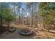 Backyard view with a stone firepit surrounded by a seating area with trees in the background at 7420 Colony Ct, Cumming, GA 30041