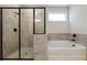 Close up of a bathroom featuring a tiled shower with glass door and soaking tub under a window at 2526 Knob Creek Dr, Snellville, GA 30078