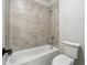 Tiled tub and shower combination with a white toilet, combining functionality and a clean aesthetic at 2526 Knob Creek Dr, Snellville, GA 30078
