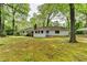 View of the house from the large backyard featuring a covered parking area and lush greenery at 2963 Williams Pl, Snellville, GA 30078