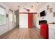 Modern living area with wood floors, a red sliding barn door, TV, and a retro mini-fridge at 3078 Semmes St, East Point, GA 30344
