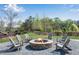 Stone fire pit with Adirondack chairs, set in a mulched area, surrounded by trees at 3950 Grandview Manor Dr, Cumming, GA 30028